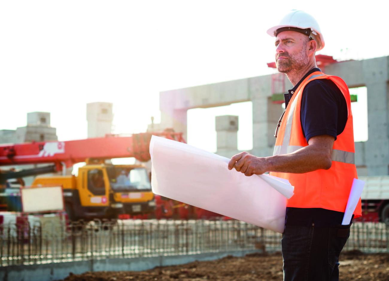 Surveyor looking at paper plans on a construction site