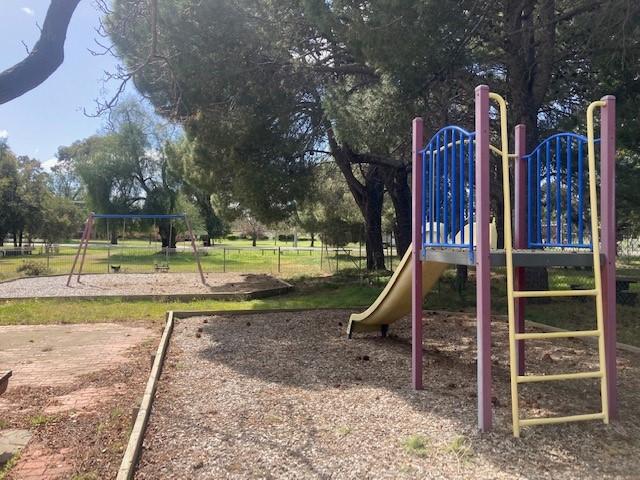 A photo of the slide and swings at the Elmore Tennis Courts Playspace.