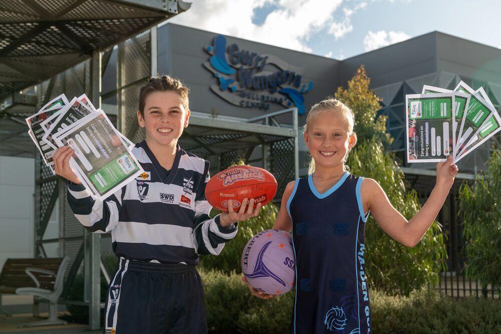 Two kids in sports uniforms with healthy sports rewards vouchers