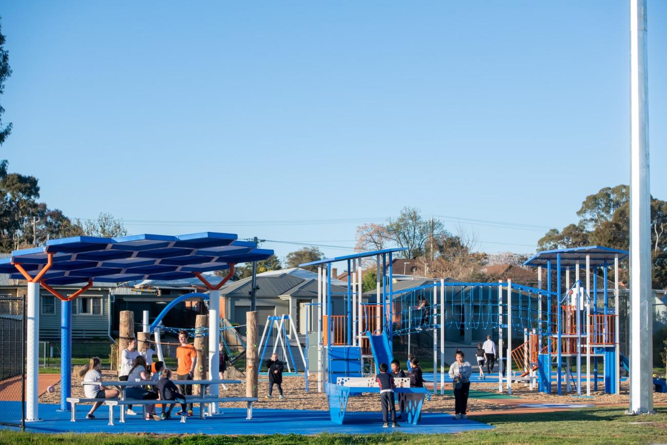 A wide photo Truscott Reserve play space, with families and children enjoying the sheltered seating and equipment