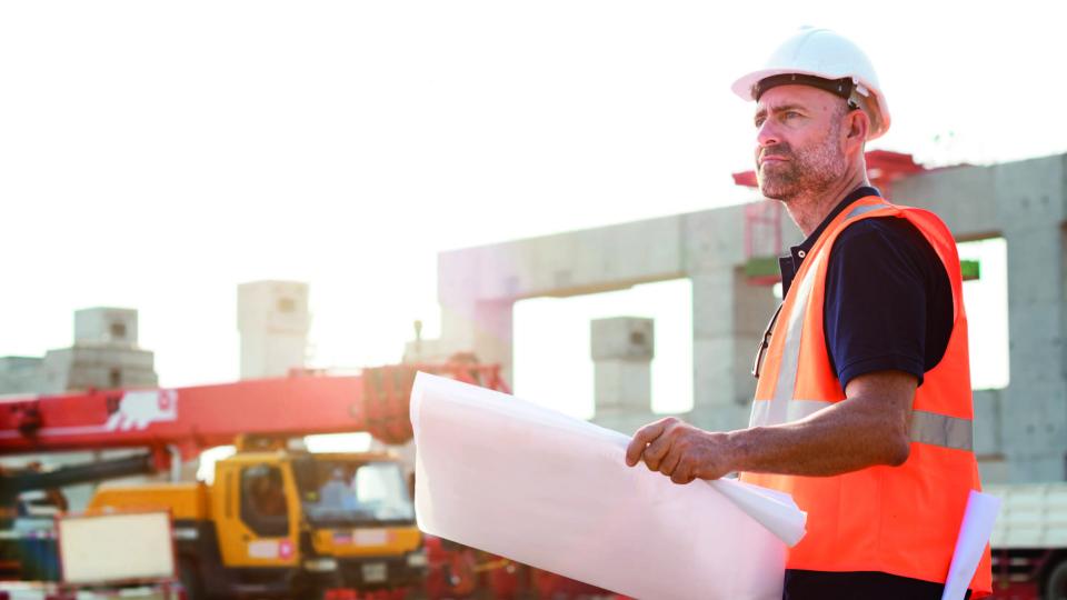 Surveyor looking at paper plans on a construction site