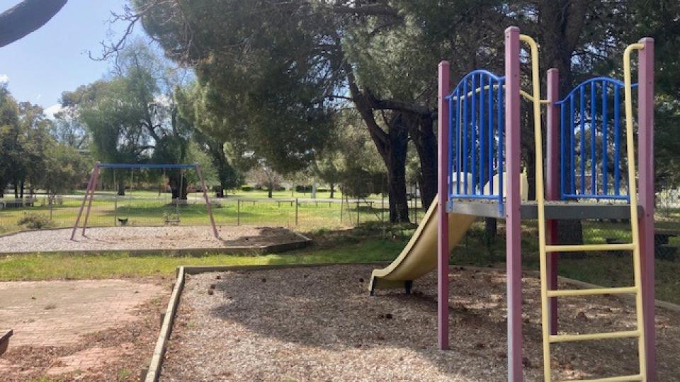A photo of the slide and swings at the Elmore Tennis Courts Playspace.