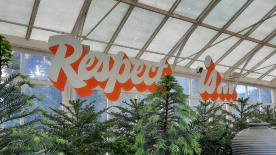 Sign stating 'Respect is...' hanging above plants