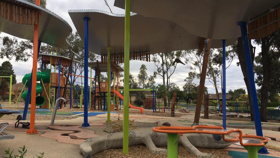 Shelters over a lizard sculpture with playground equipment in the background