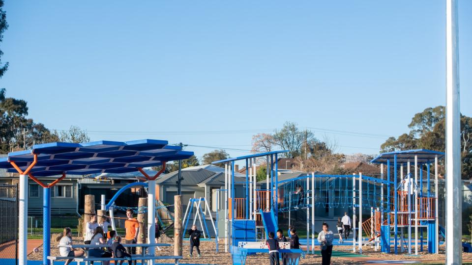 A wide photo Truscott Reserve play space, with families and children enjoying the sheltered seating and equipment